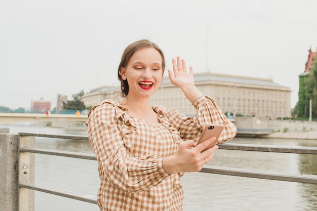 Beautiful girl communicates by video call on the street