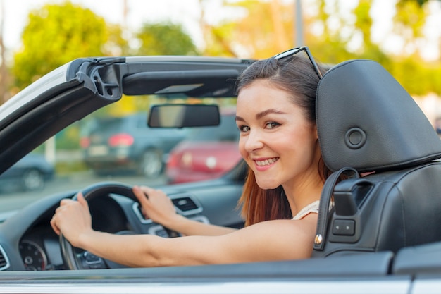 Beautiful girl in the  convertible cabrio car on a sunny day in a city