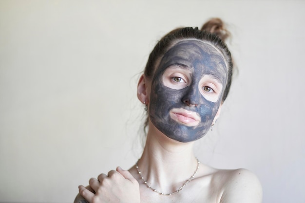 Beautiful girl in a cosmetic clay mask a young girl with a\
cosmetic clay mask on her face