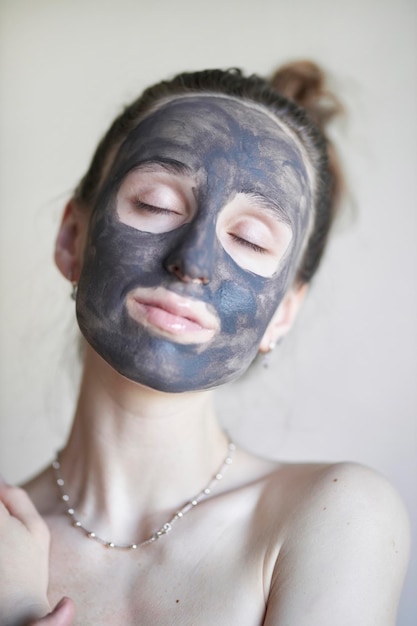 Beautiful girl in a cosmetic clay mask a young girl with a
cosmetic clay mask on her face