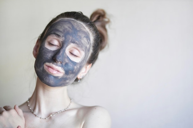 beautiful girl in a cosmetic clay mask A young girl with a cosmetic clay mask on her face