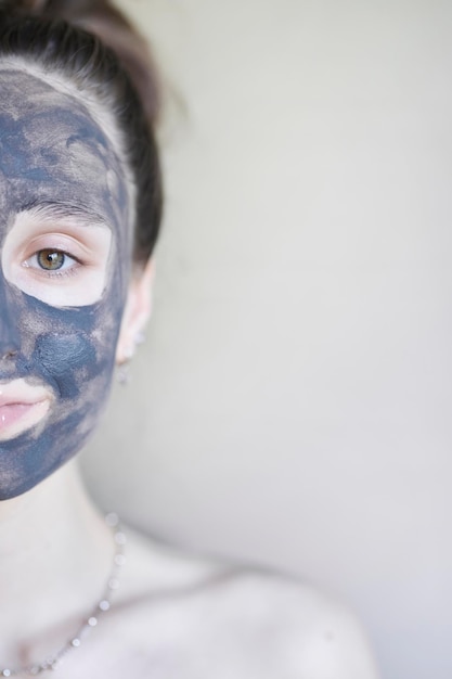 beautiful girl in a cosmetic clay mask A young girl with a cosmetic clay mask on her face