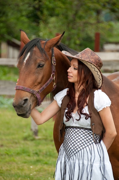 A beautiful girl in a cowboy hat with a horse