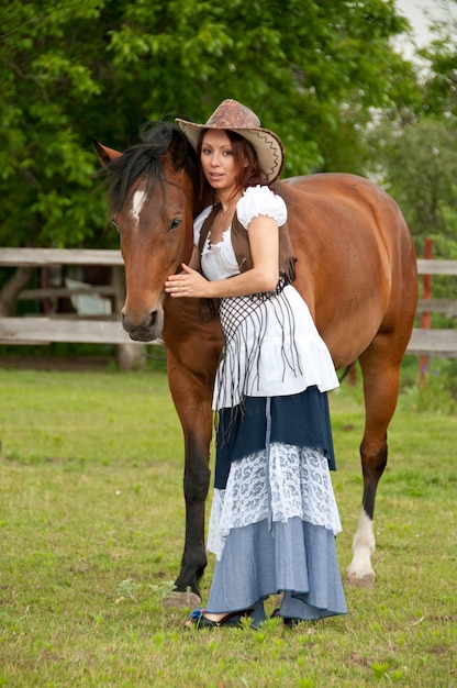 A beautiful girl in a cowboy hat with a horse