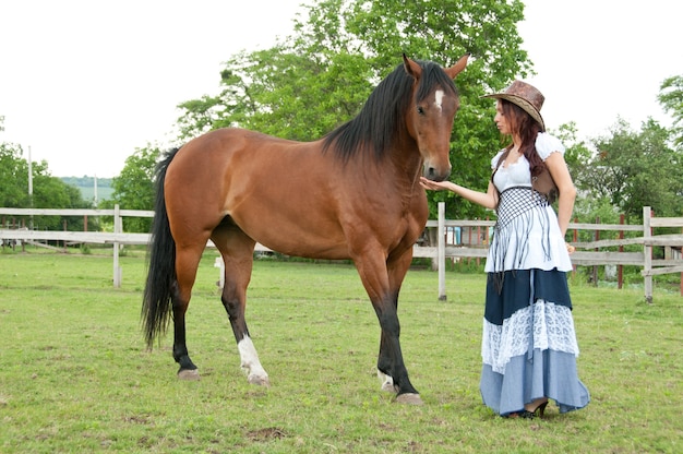 A beautiful girl in a cowboy hat with a horse