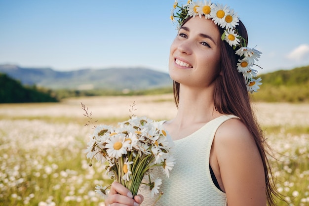 Beautiful girl in daisy field Summer sunset happy young lady and springgreen nature harmony concept Carefree happy brunette woman with healthy wavy hair having fun outdoor in nature