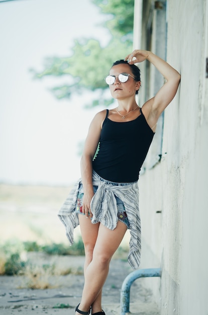 Beautiful girl in denim shorts and black tank top grunge style