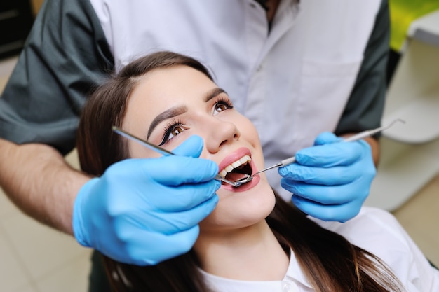 Bella ragazza sulla sedia dentale all'esame dal dentista