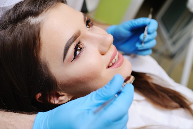 Bella ragazza sulla sedia dentale all'esame dal dentista