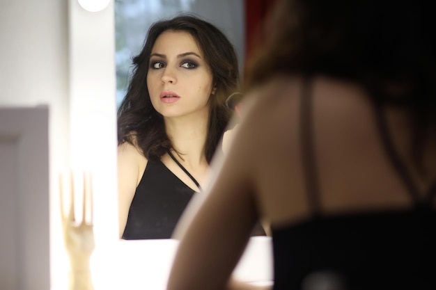 Beautiful girl doing makeup in front of a mirror