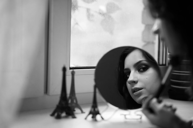 Красивая девушка делает макияж перед зеркалом
