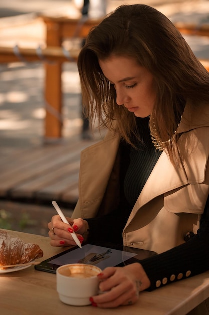 beautiful girl draws in a cafe on a graphics tablet
