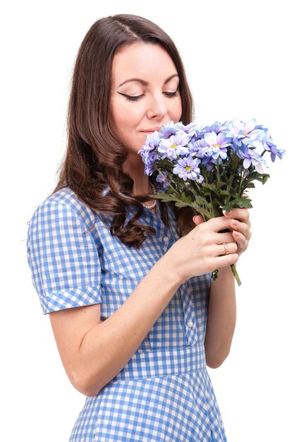 Beautiful girl in a dress in a blue cage with flowers chrysanthemums in hands on a white background