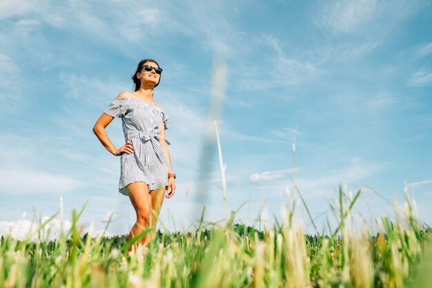 Beautiful girl in dress on green field. People and nature concept