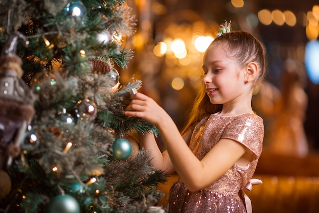 エレガントなクリスマスツリーの近くのドレスの美しい少女