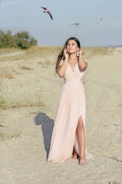 Beautiful girl in a dress near the sea with seagulls