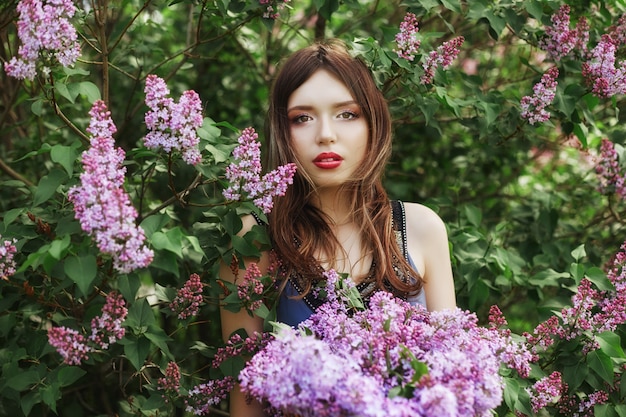 Beautiful girl in a dress posing in Bush of lilacs