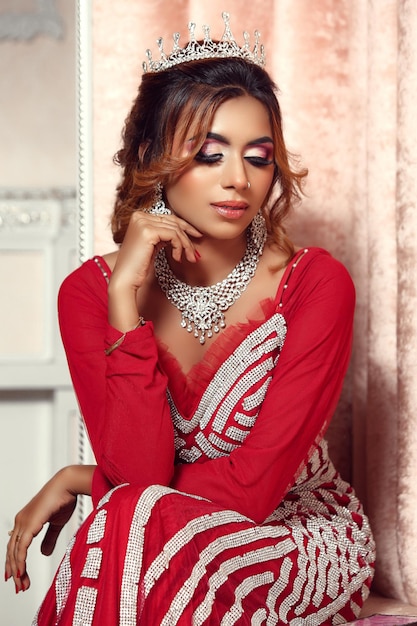 Beautiful girl dressed as a queen in red dress closeup