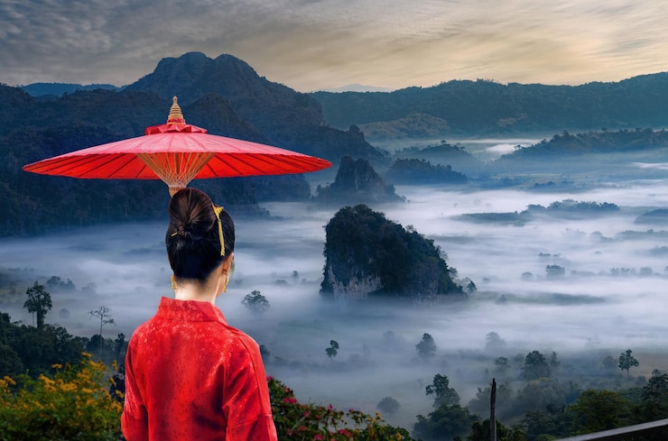 Photo beautiful girl dressed in thai lanna dress standing with an umbrella watching the sea of mist