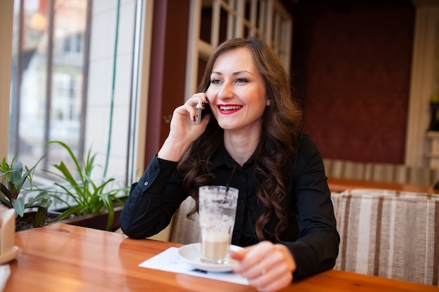 Beautiful girl drinking coffee and talking on the phone