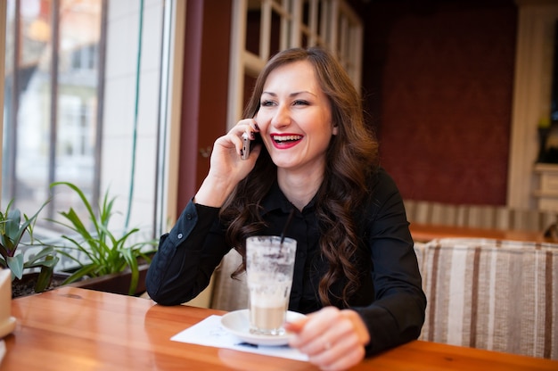 コーヒーを飲み、電話で話している美しい少女