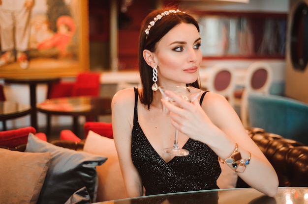 A beautiful girl drinks martini in the hotel lobby