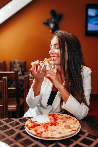 Красивая девушка ест пиццу в ресторане
