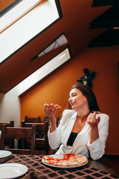 Beautiful girl eating pizza at restaurant