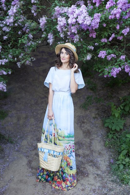 beautiful girl enjoying lilac on summer day young woman in dress  in lilac garden