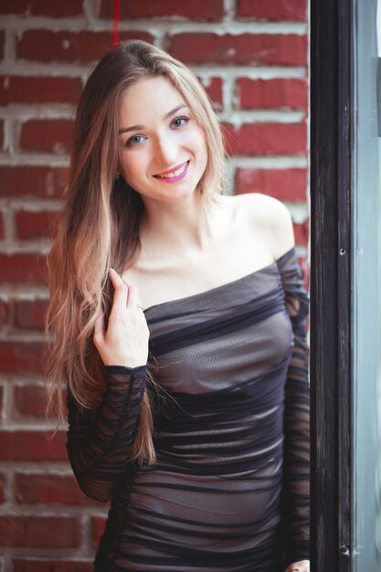 Beautiful girl in an evening dress posing against a brick wall