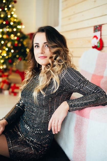 Beautiful girl in evening dress sitting on the background of Christmas decorations