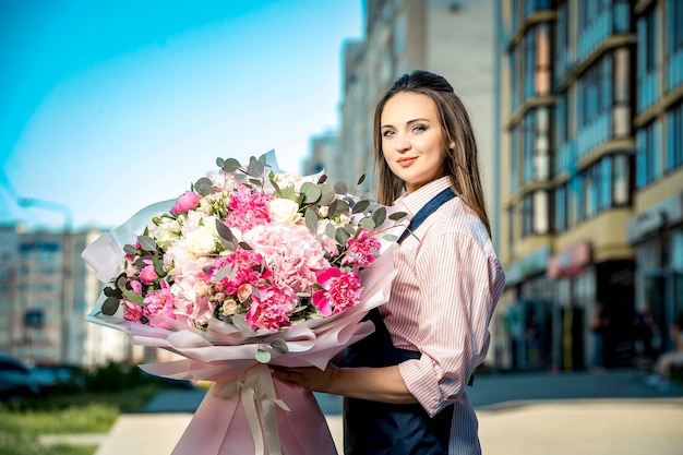 花の大きな花束を持つ美しい女の子の花屋市内の花の配達