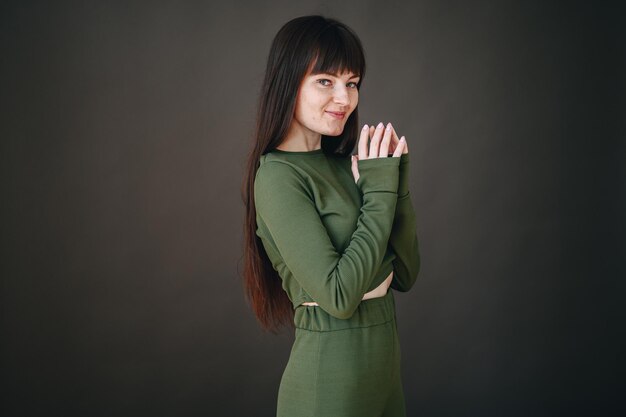 A beautiful girl folded her palms in front of her looking at the camera A girl in a knitted dress