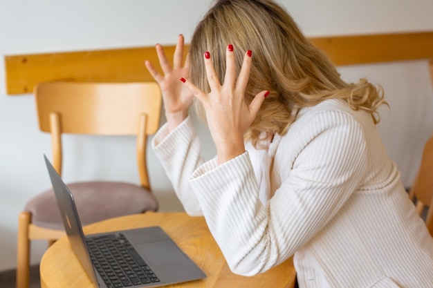 Beautiful girl freelancer feeling tired and stressed while using a laptop and working remotely.