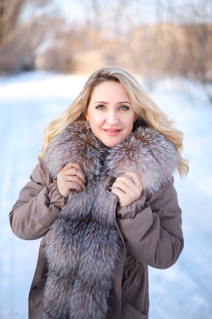 Beautiful girl in a fur coat in a winter park