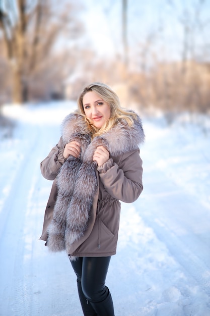 Beautiful girl in a fur coat in a winter park