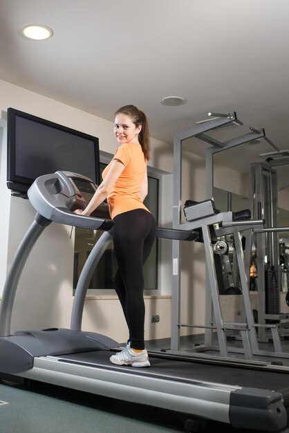 Beautiful girl goes in for sports on the simulator in the gym