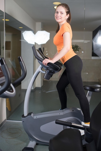 Beautiful girl goes in for sports on the simulator in the gym