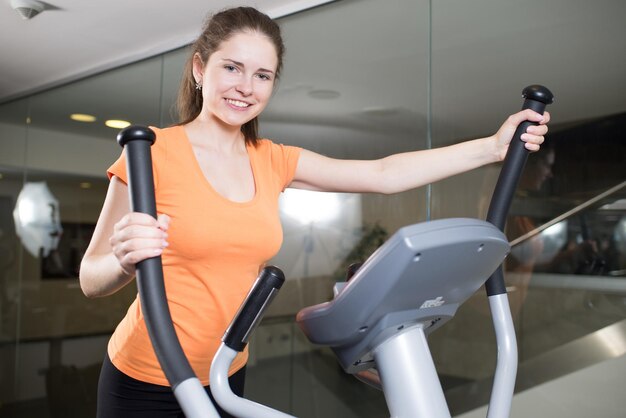 Beautiful girl goes in for sports on the simulator in the gym