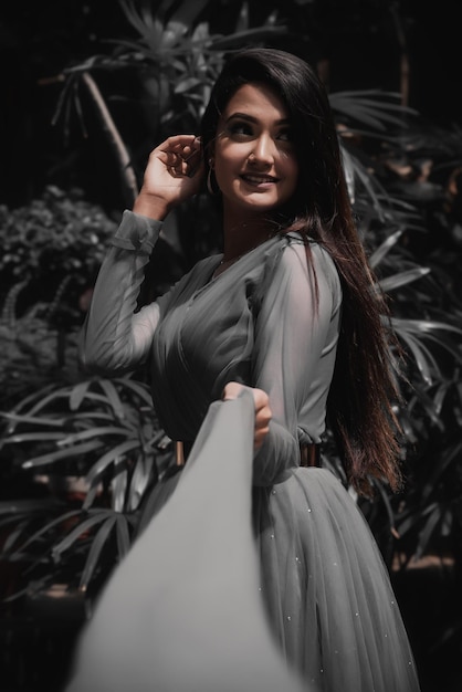 Photo a beautiful girl in a gray gown dress posing in front of a palm tree