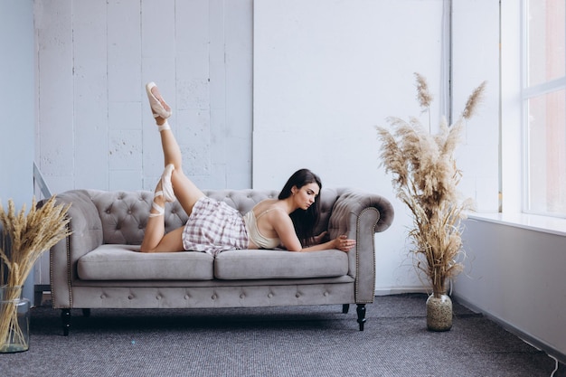 Beautiful girl gymnast at home performs exercises on the couch