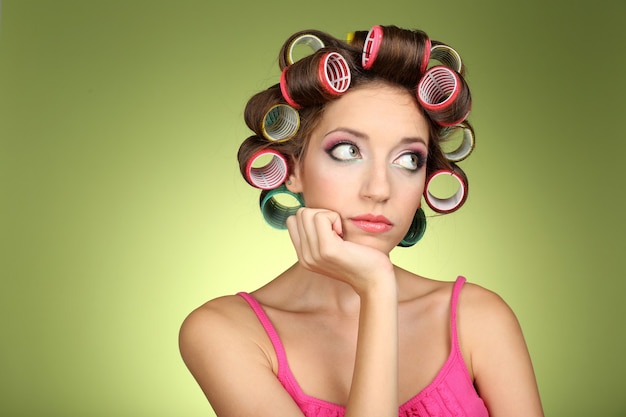 Beautiful girl in hair curlers on green