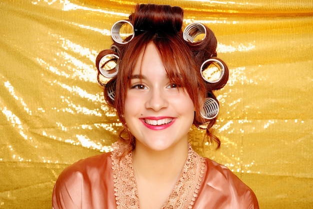 Beautiful girl in hair curlers isolated on golden background