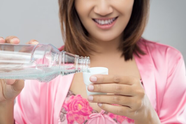 Beautiful girl hands pouring mouthwash into bottle cap