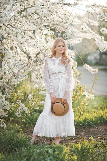 A beautiful girl in a hat among the flowering trees 2727