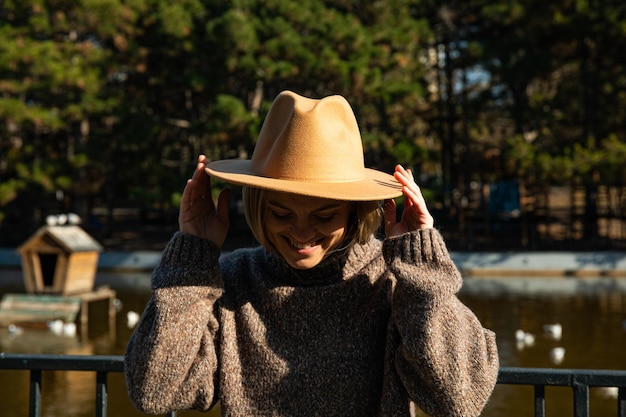 A beautiful girl in a hat walks in an autumn park with coffee