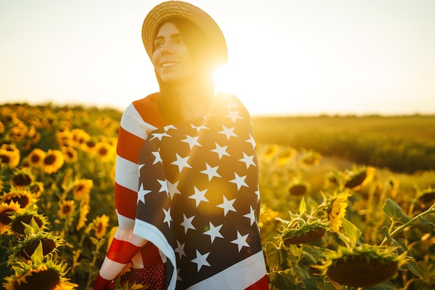 Beautiful girl in hat with American flag in a sunflower field 4th of July Independence Day