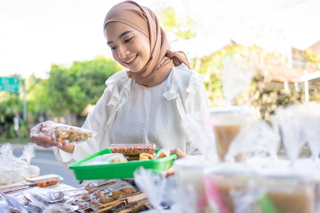 A beautiful girl in a headscarf holding a snack wrapped in plastic will be bought