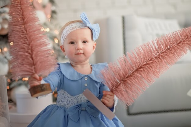 クリスマスツリーを保持している美しい少女幸せな赤ちゃんはクリスマスと新年を祝う