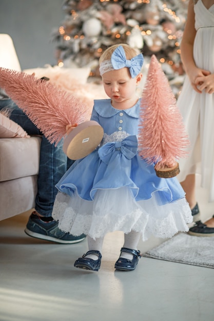 Beautiful girl holding Christmas tree Happy baby celebrates Christmas and New Year